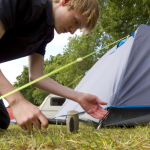 A man setting up a tent for a couple.